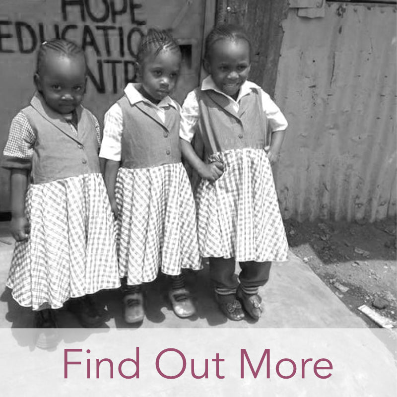 Three beautiful Kenyan school girls aged around 6 years old in school uniform smiling for the camera