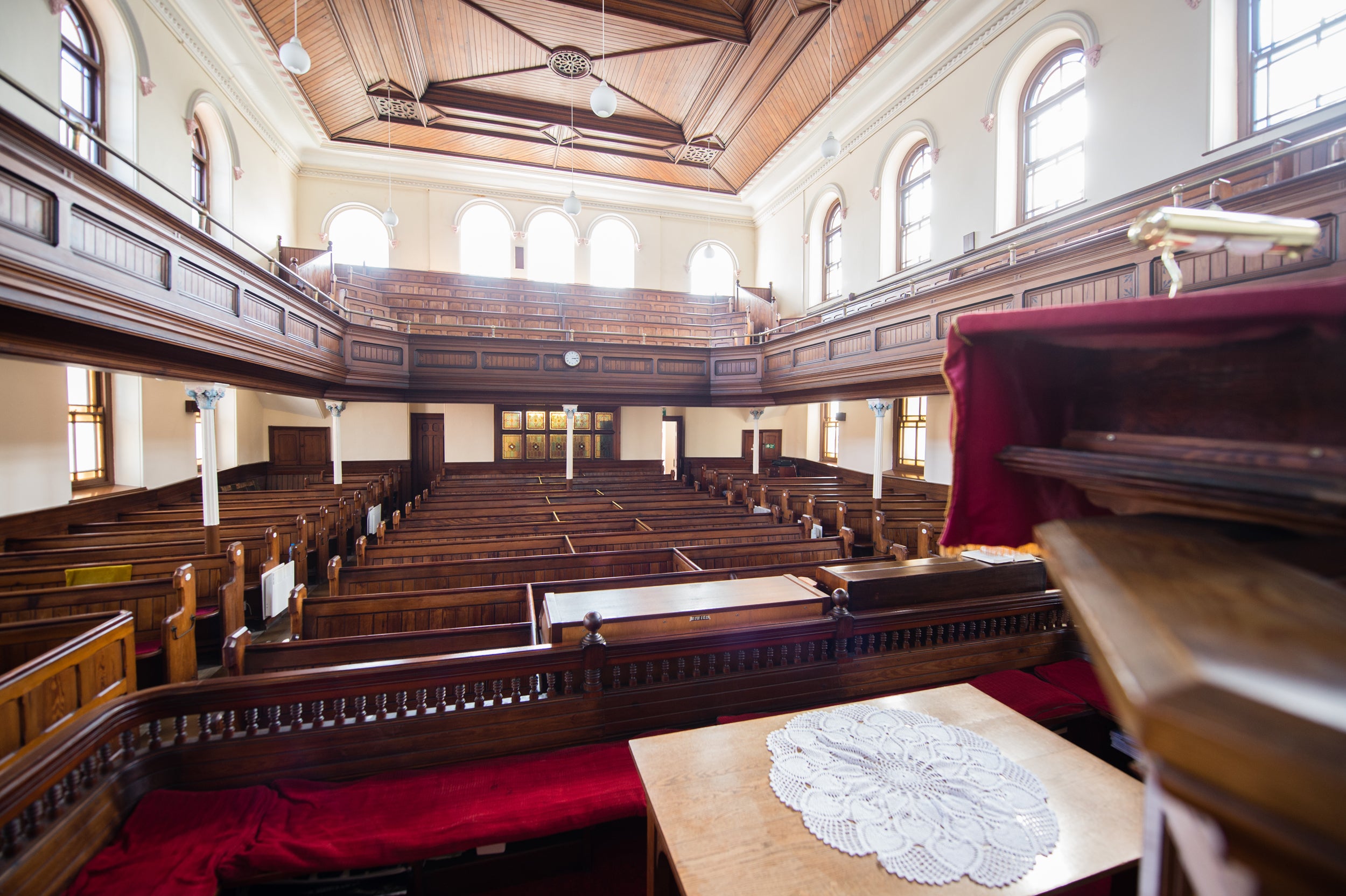 An image of the inside of Morah Chapel from the stage. There are many rows of wooden pews and a balcony from left to right. 