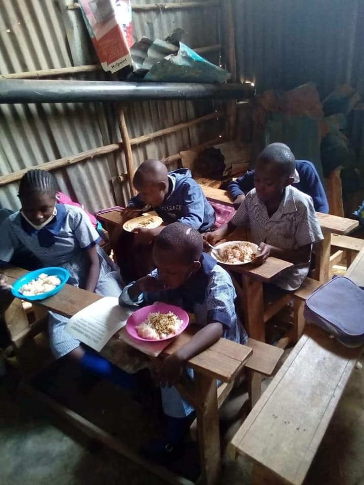 A group of Kenya school children having lunch in their classroom.