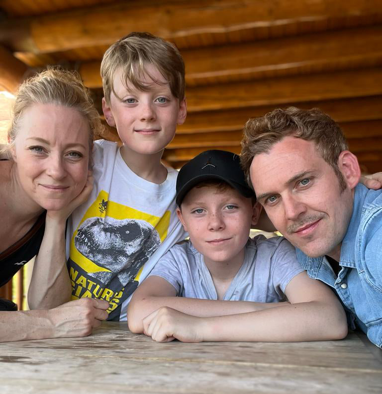 A family photo of the thompson family leaning on a table.